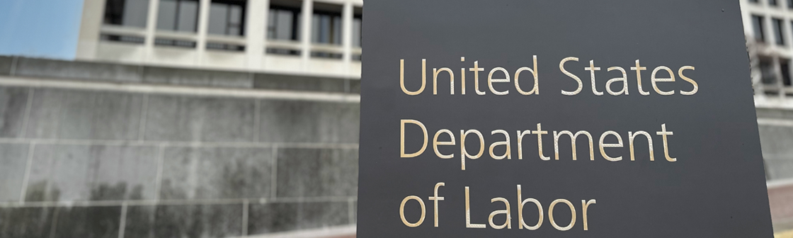 US Department of Labor signage on gray background in front of government building,